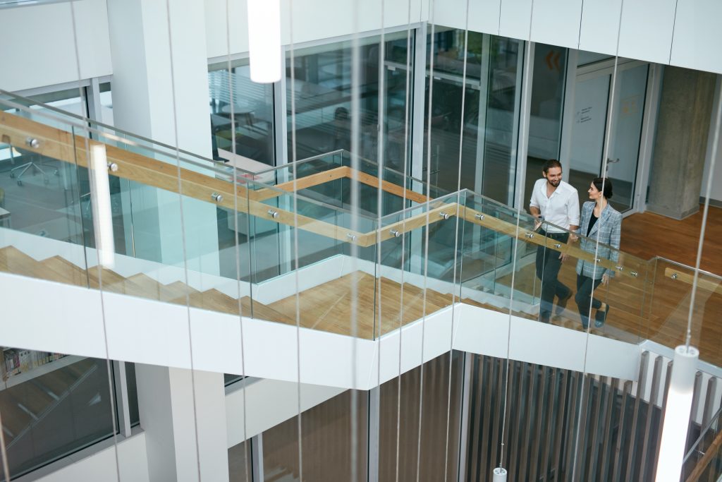 Business People Working In Modern Office. Man And Woman Walking On Stairs In Contemporary Business Centre Interior. High Resolution